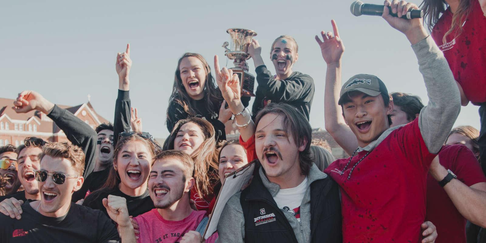 Students cheer and hold a trophy during Homecoming celebrations